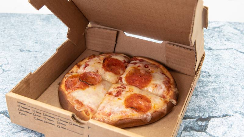 Small personal pan pizza cut into four slices and delivered in cardboard box.