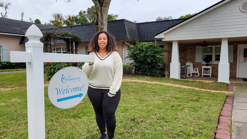 Amanda Brochu stands next to a sign outside The Russell Home.