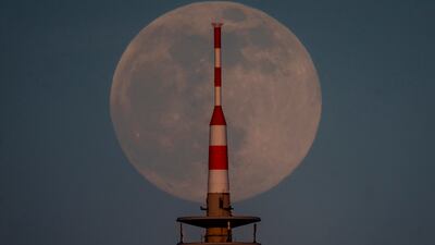 The full moon rises behind the television tower in Frankfurt, Germany, Monday, April 26, 2021.
