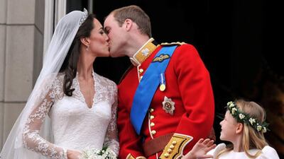Watched by one of the bridesmaids, Prince William and his wife Kate Duchess of Cambridge, kiss on the balcony of Buckingham Palace in London,Friday April 29, 2011, following their wedding at Westminster Abbey. (John Stillwell ASSOCIATED PRESS)