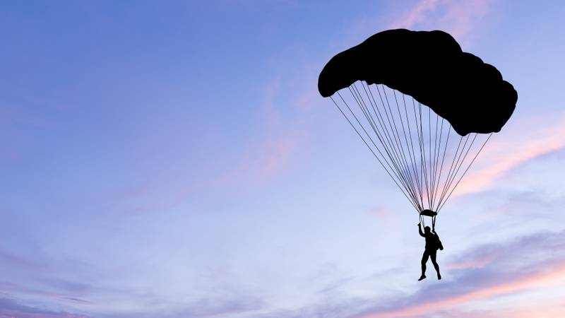 Silhouette of parachute on sunset background