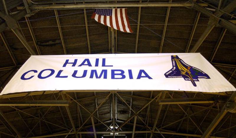 A banner that reads "Hail Columbia" with an American flag hanging over it greets workers to Nose Dock Six, where space shuttle Columbia debris is being catalogued and temporarily warehoused at Barksdale Air Force Base February 10, 2003 in Louisiana. Debris collected since the February 1, 2003 accident has been brought to the base as part of the investigation into the spacecraft's breakup.  (Photo by Tony Gutierrez - Pool/Getty Images)